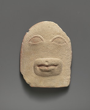 A piece of limestone with a subtle relieve of eyes and a mouth