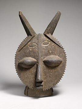 A wooden headdress of a face with sharp geometric features