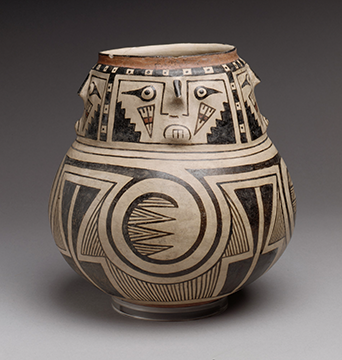 A decorative jar with four illustrated faces facing four different directions