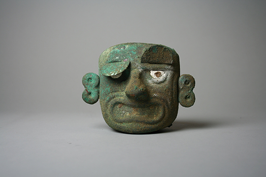 A green mask with face with exaggerated figures