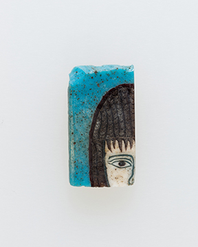 A piece of a glass mosaic with a partial female face